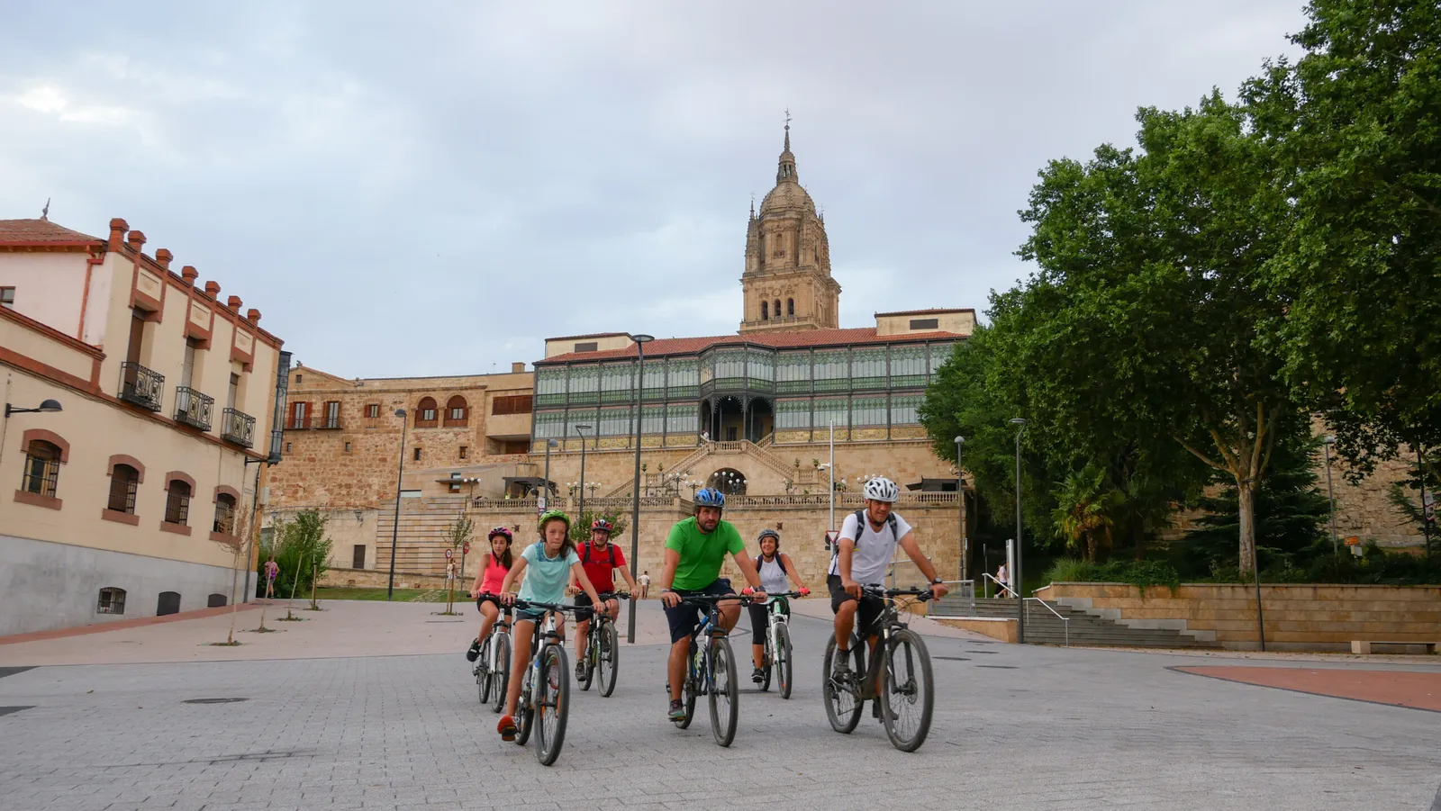 Grupo de personas en bicicleta por un paseo de Salamanca, con la catedral y la Casa Lis al fondo, en la ruta ciclista de la Batalla de los Arapiles.